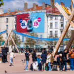 Campagne SNCF sur toile microperforée à Lyon, vue de jour illustrant la forte affluence sur la place Bellecour.