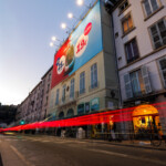 Affichage XXL en toile microperforée à Lyon pour la SNCF, vue de côté de nuit de près sur l'échafaudage de la place Bellecour.