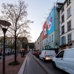 Affichage XXL en toile microperforée à Lyon pour la SNCF, vue de côté de nuit sur l'échafaudage de la place Bellecour.