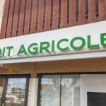 Enseigne lumineuse verte marquant l'entrée, dans le cadre de la signalétique d'agence bancaire à Saint-Paul-en-Chablais.