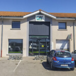 Vue de face de la signalétique d'agence bancaire à Apprieu, avec une enseigne lumineuse verte sous le toit et des adhésifs sur vitrage