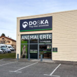 Vue globale de loin de l'enseigne LightBox, de la vitrophanie et du panneau extérieur du magasin DO&KA à Chatte.