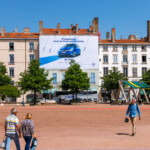 Vue lointaine de jour montrant l'intégration urbaine parfaite pour financer des travaux de façade à Lyon, place Bellecour.