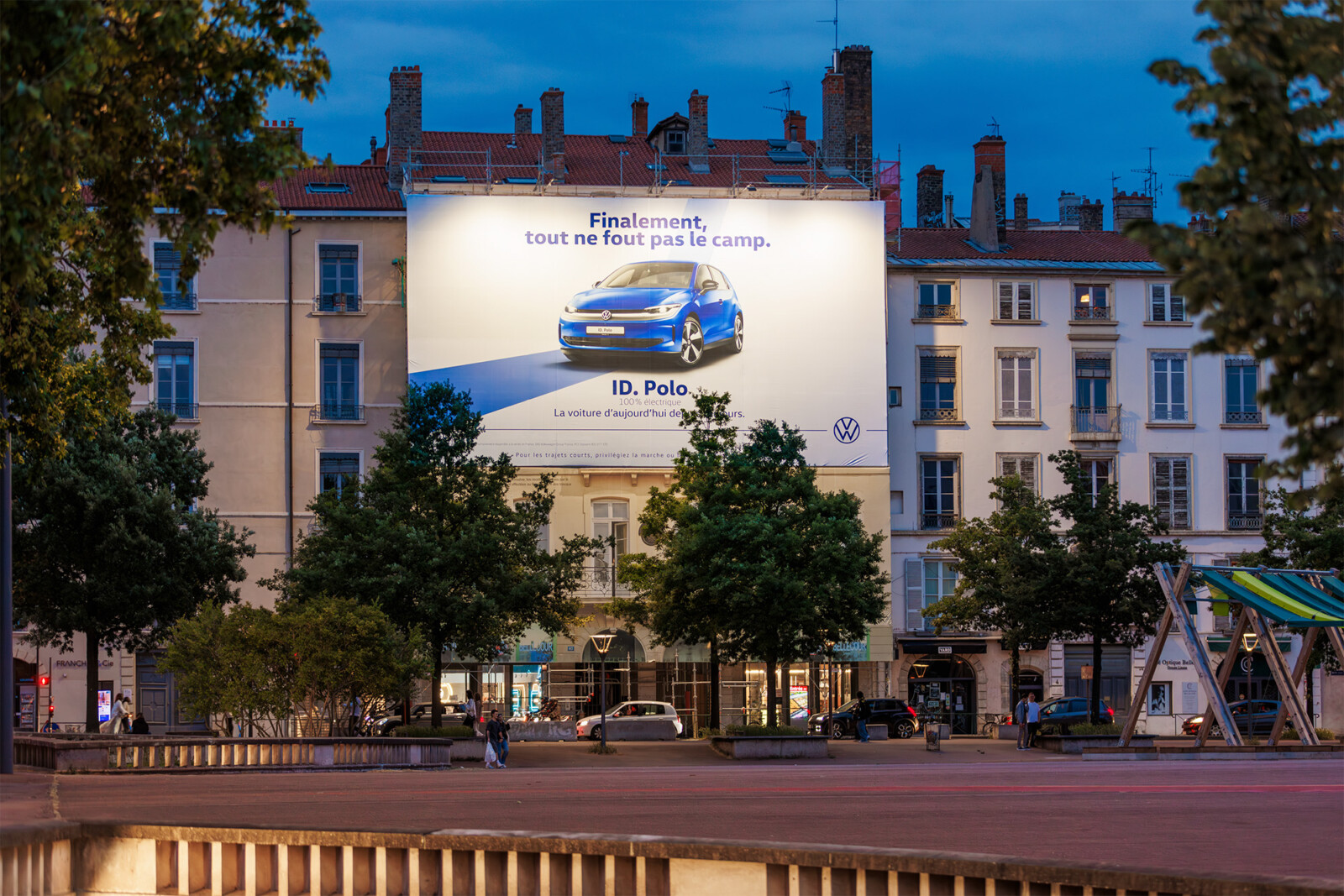 Vue de face de nuit du dispositif Volkswagen illuminé qui finance les travaux de façade sur la place Bellecour à Lyon.