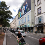 Vue de côté en journée de la campagne grand format McDonald's, s'intégrant au-dessus de la circulation de la place Bellecour à Lyon.