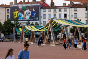 Vue lointaine de jour de face illustrant l'intégration urbaine parfaite de cette campagne grand format au cœur de Lyon, sur la place Bellecour.