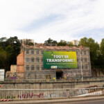 Vue globale d'une grande toile sur échafaudage de chantier de réhabilitation à Lyon.
